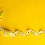 Banana and tape measure on yellow background. Diet concept.