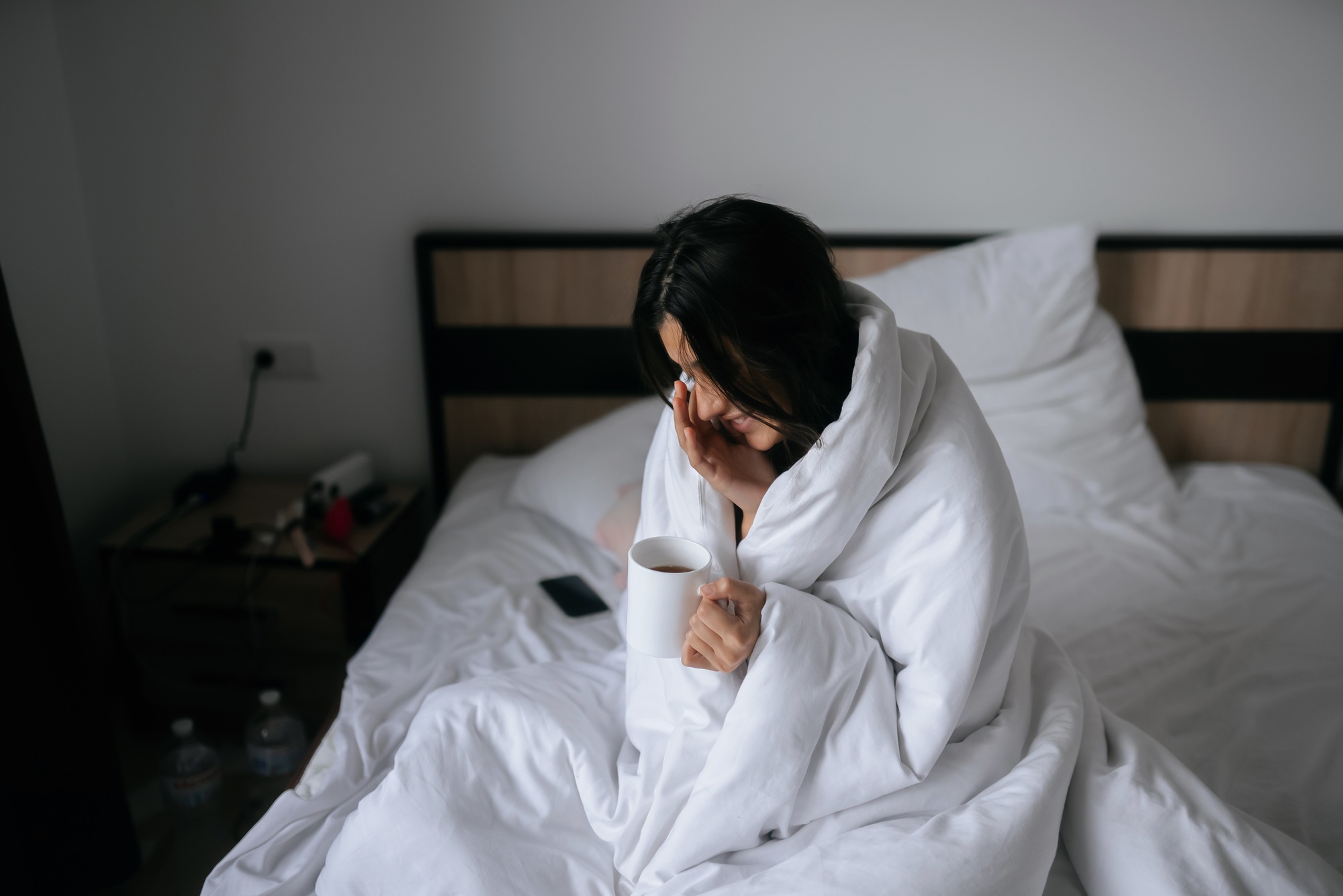 Woman wrapped in a blanket and holds a mug